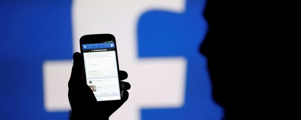 A man is silhouetted against a video screen with a Facebook logo A man is silhouetted against a video screen with a Facebook logo - Sputnik International
