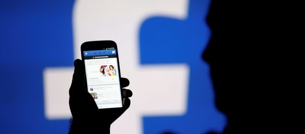 A man is silhouetted against a video screen with a Facebook logo as he poses with a smartphone in this photo illustration taken in Zenica. A man is silhouetted against a video screen with a Facebook logo as he poses with a smartphone in this photo illustration taken in Zenica. - Sputnik International