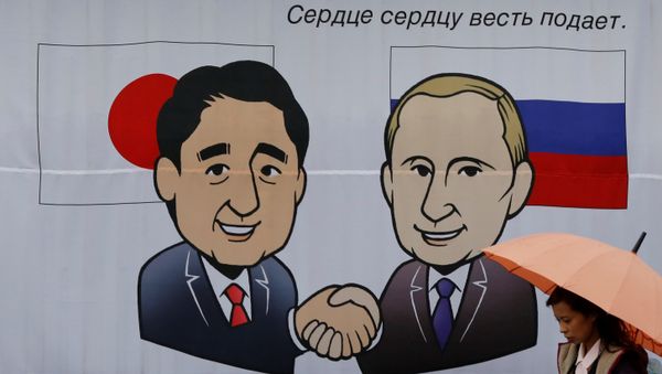 A woman walks past a banner showing Japan's Prime Minister Shinzo Abe and Russian President Vladimir Putin at the Senzaki station in Nagato, Yamaguchi prefecture, Japan, December 14, 2016 - Sputnik International