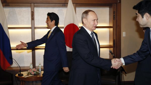 Russian President Vladimir Putin, center, shakes hands with a Japanese official as Japanese Prime Minister Shinzo Abe, left, prepares to greet a member of the Russian delegation during their meeting in Nagato, Japan, Thursday, Dec. 15, 2016. Russian President Vladimir Putin, center, shakes hands with a Japanese official as Japanese Prime Minister Shinzo Abe, left, prepares to greet a member of the Russian delegation during their meeting in Nagato, Japan, Thursday, Dec. 15, 2016. - Sputnik International