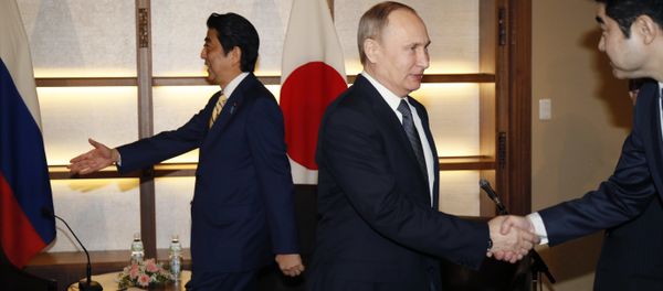 Russian President Vladimir Putin, center, shakes hands with a Japanese official as Japanese Prime Minister Shinzo Abe, left, prepares to greet a member of the Russian delegation during their meeting in Nagato, Japan, Thursday, Dec. 15, 2016. Russian President Vladimir Putin, center, shakes hands with a Japanese official as Japanese Prime Minister Shinzo Abe, left, prepares to greet a member of the Russian delegation during their meeting in Nagato, Japan, Thursday, Dec. 15, 2016. - Sputnik International