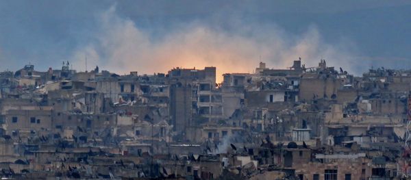 A general view shows smoke and flames rising from buildings in Aleppo's southeastern al-Zabdiya neighbourhood following government strikes on December 14, 2016. - Sputnik International