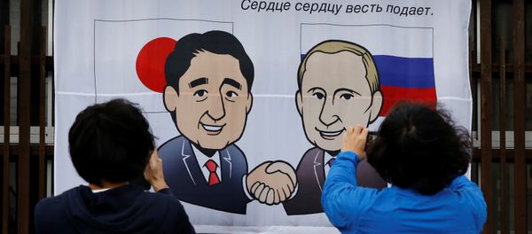 People take photos of a banner showing Japan's Prime Minister Shinzo Abe and Russian President Vladimir Putin at the Senzaki station in Nagato, Yamaguchi prefecture, Japan, December 14, 2016, a day before their summit meeting. The words on top reads, A new start from here in Nagato. - Sputnik International