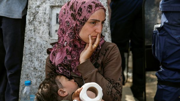 A woman sits with her child after migrants and refugees tried to open the border fence at a makeshift camp at the Greek-Macedonian border near the village of Idomeni, Greece, April 7, 2016. - Sputnik International