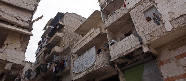 Residents in a government-held part of Aleppo's Salaheddin neighbourhood look out from the balconies of their damaged houses at the road on which the convoy evacuating civilians and rebel fighters from the last rebel-held neighbourhood in the northern Syrian city were supposed to pass - Sputnik International