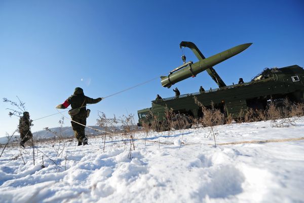 Russian soldiers watch a transporter-loader place an Iskander-M shorter-range missile onto a launcher during an exercise - Sputnik International