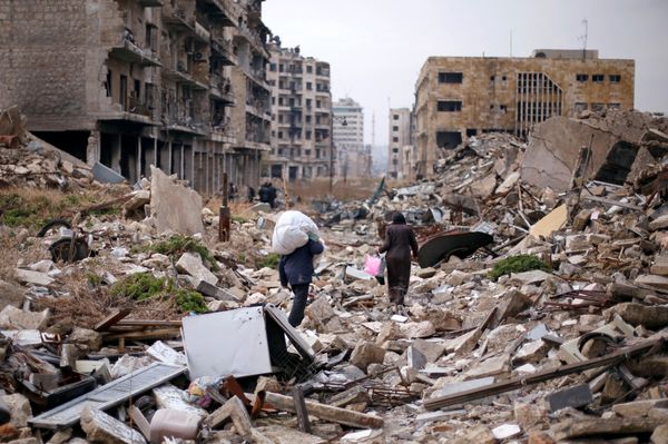 People walk amid the rubble as they carry belongings that they collected from their houses in the government controlled area of Aleppo, Syria December 17, 2016 - Sputnik International