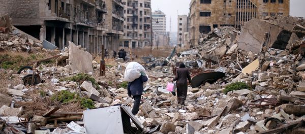 People walk amid the rubble as they carry belongings that they collected from their houses in the government controlled area of Aleppo, Syria December 17, 2016 - Sputnik International
