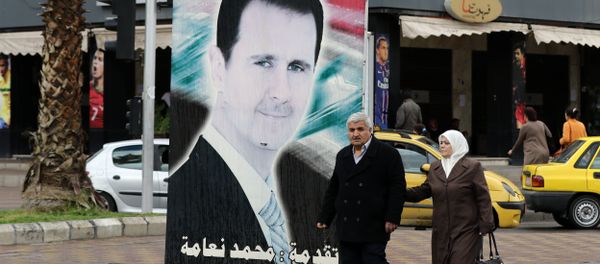 Syrians walk past a portrait of President Bashar al-Assad in the capital Damascus on March 15, 2016 Syrians walk past a portrait of President Bashar al-Assad in the capital Damascus on March 15, 2016 - Sputnik International
