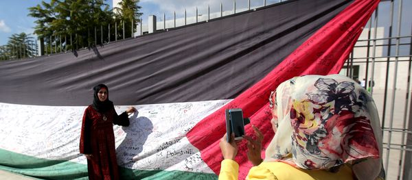 A Palestinian woman takes a picture of a 66-meter-long Palestinian flag - Sputnik International
