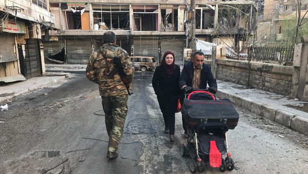Local residents pass a soldier on a street in Aleppo. - Sputnik International