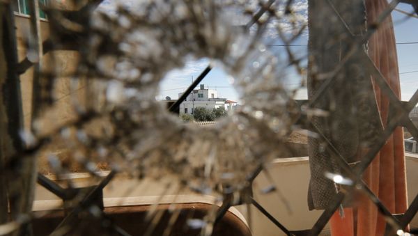 A nearby house is pictured through a bullet hole in a window inside a building that was the site of clashes between Jordanian police and Islamist militant gunmen in the village of Garifla, in Karak, Jordan, December 21, 2016 - Sputnik International