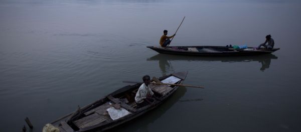 An Indian fisherman paddles a country boat as he leaves for fishing as another man sits in an anchored boat in the river Brahmaputra in Gauhati, India An Indian fisherman paddles a country boat as he leaves for fishing as another man sits in an anchored boat in the river Brahmaputra in Gauhati, India - Sputnik International