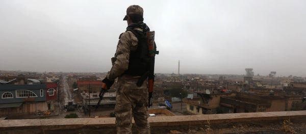 An Iraqi security member stands guard as Iraqi Christians attend a Christmas Eve service at the Saint John's church (Mar Yohanna church) in the town of Qaraqosh (also known as Hamdaniya), 30 kms east of Mosul, on December 25, 2016 - Sputnik International