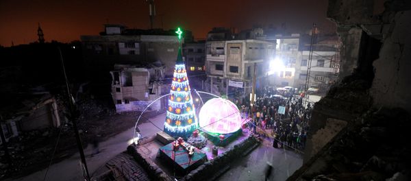 People gather by a Christmas tree near damaged buildings during Christmas eve in al-Hamidiyah neighbourhood in the old city of Homs, Syria December 24, 2016 - Sputnik International