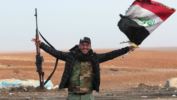 An Iraqi forces member flashes his gun as he waves his national flag in the village of Arabat, south of Mosul, as temperatures continue to drop, on December 1, 2016 - Sputnik International