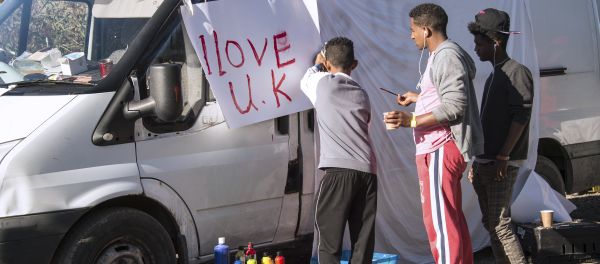 Young migrants paint a sheet of paper with the lettering 'I love UK' in the 'Jungle' migrant camp, in Calais, northern France, on October 31, 2016, during a massive operation to clear the squalid settlement where 6,000-8,000 people have been living in dire conditions Young migrants paint a sheet of paper with the lettering 'I love UK' in the 'Jungle' migrant camp, in Calais, northern France, on October 31, 2016, during a massive operation to clear the squalid settlement where 6,000-8,000 people have been living in dire conditions - Sputnik International