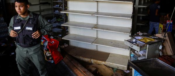 A Venezuelan National Guard stands guard as workers recover the valuables after a supermarket was looted in Ciudad Bolivar - Sputnik International