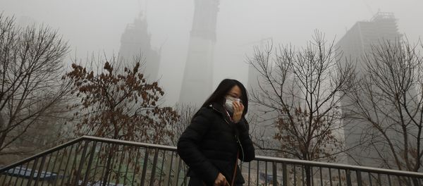A woman wearing a mask for protection against air pollution walks on a pedestrian overhead bridge in Beijing as the capital of China is shrouded by heavy smog on Tuesday, Dec. 20, 2016 - Sputnik International