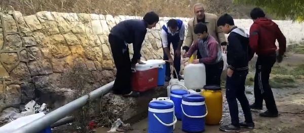 This frame grab from video provided By Yomyat Kzefeh Hawen Fi Dimashq (Diary of a Mortar Shell in Damascus), a Damascus-based media outlet that is consistent with independent AP reporting, shows Syrian residents filling up buckets and gallons of spring water from a pipe on the side of the road, in Damascus, Syria - Sputnik International