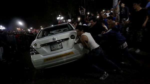 Demonstrators push over a vehicle of Multimedios TV network during a protest against the rising prices of gasoline enforced by the Mexican government at the Macroplaza in Monterrey, Mexico, January 5, 2017 Demonstrators push over a vehicle of Multimedios TV network during a protest against the rising prices of gasoline enforced by the Mexican government at the Macroplaza in Monterrey, Mexico, January 5, 2017 - Sputnik International
