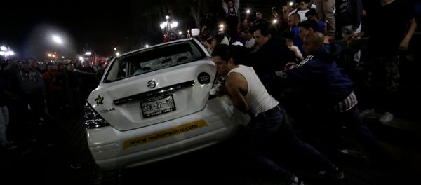 Demonstrators push over a vehicle of Multimedios TV network during a protest against the rising prices of gasoline enforced by the Mexican government at the Macroplaza in Monterrey, Mexico, January 5, 2017 Demonstrators push over a vehicle of Multimedios TV network during a protest against the rising prices of gasoline enforced by the Mexican government at the Macroplaza in Monterrey, Mexico, January 5, 2017 - Sputnik International