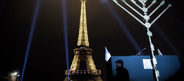 A member of the Jewish community stands near a Menorah (Hanukkah), a nine-branched candelabrum, before the lighting of two branches in front of the Eiffel tower in Paris on December 25, 2016. - Sputnik International