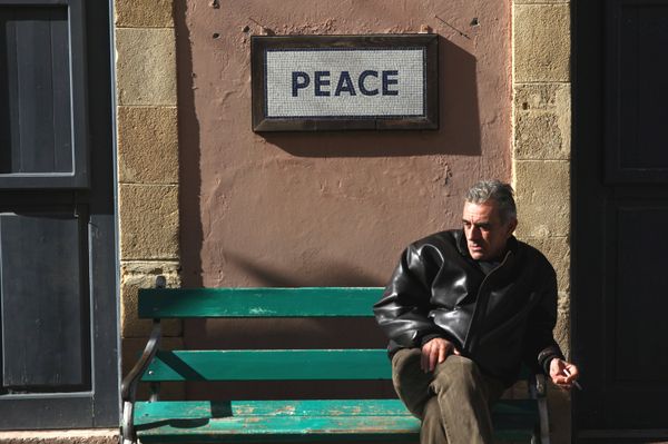 A man sits on a bench under a peace sign near the UN-controlled buffer zone in Nicosia, Cyprus January 9, 2017. - Sputnik International