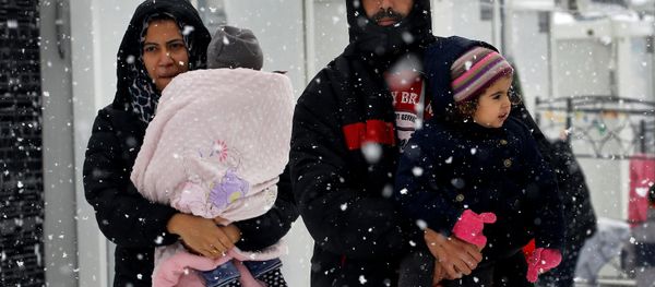 Stranded Syrian refugees carry their children through a snow storm at a refugee camp north of Athens, Greece January 10, 2017. Stranded Syrian refugees carry their children through a snow storm at a refugee camp north of Athens, Greece January 10, 2017. - Sputnik International