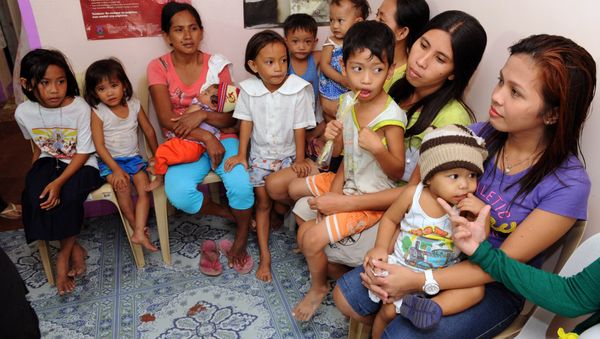 In this photo taken January 16, 2013, a health worker (C) shows an intrauterine device (IUD) to mothers at the Likhaan Center for Women's Health in Baseco, a massive slum in Manila where more than 60,000 people compete for space. - Sputnik International