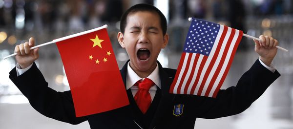 A little boy who is waiting to greet U.S. Secretary of State Hillary Rodham Clinton at the National Museum in Beijing makes a face while holding U.S. and Chinese flags Friday, May 4, 2012 - Sputnik International
