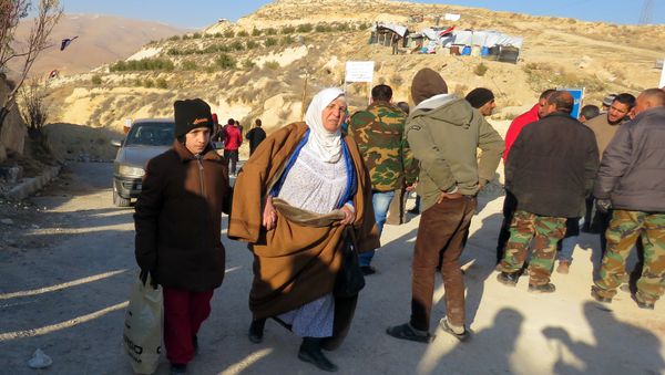 A Syrian boy and his grandmother are seen at an army checkpoint, as rebel fighters and their families prepare to leave the town of Deir Kanun in the Wadi Barada region, on January 11, 2017, as part of a ceasefire deal with the Syrian government - Sputnik International
