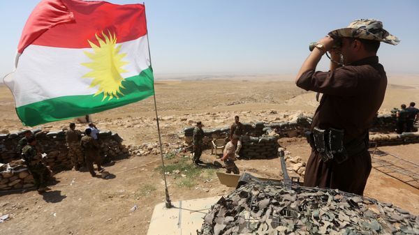 A flag of the autonomous Kurdistan region flies as Iraqi Kurdish Peshmerga fighters take position to monitor the area from their front line post in Bashiqa, a town 13 kilometres north-east of Mosul (File) - Sputnik International