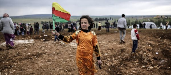 A Syrian Kurdish young woman holds the flag of the Syrian Kurdish Democratic Union Party (PYD) (File) - Sputnik International