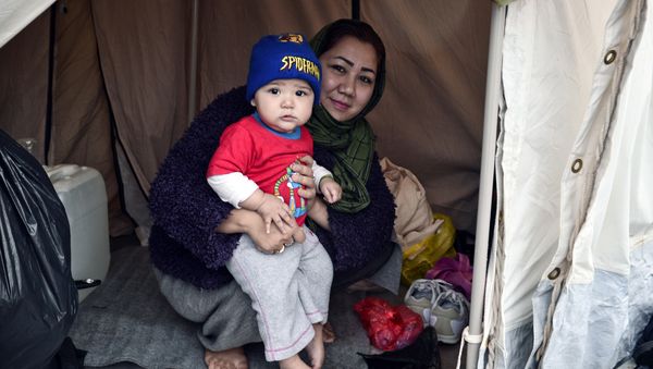 An Afghani refugee woman and mother of three poses with one of her children in their tent set up on a baseball field at a refugee camp in the Hellinikon Olympic Complex, in a southern Athens suburb, on January 11, 2017. - Sputnik International