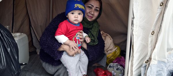 An Afghani refugee woman and mother of three poses with one of her children in their tent set up on a baseball field at a refugee camp in the Hellinikon Olympic Complex, in a southern Athens suburb, on January 11, 2017. - Sputnik International