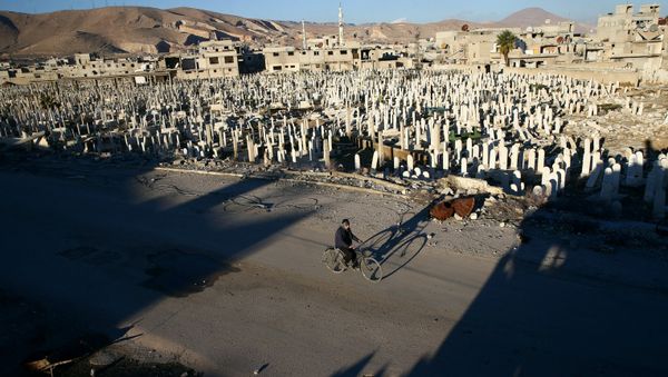 A civilian rides a bicycle past a cemetery in the rebel held besieged Douma neighbourhood of Damascus, Syria January 3, 2017 - Sputnik International