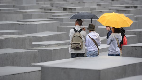 Tourists with umbrellas walk through the Holocaust Memorial on July 28, 2011 in Berlin.  - Sputnik International