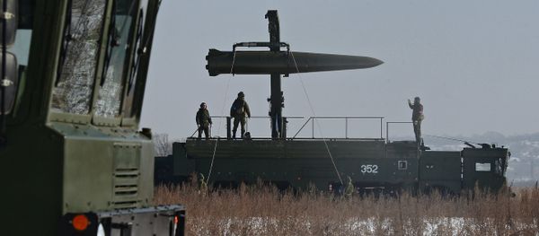 Russian soldiers watch a transporter-loader place an Iskander-M shorter-range missile onto a self-propelled launcher - Sputnik International