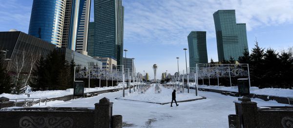 A picture taken on January 22, 2017 shows a man walking in downtown Astana, with the Baiterek monument seen in the background - Sputnik International