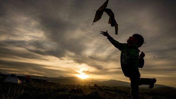 A refugie boy flies his kite at sunset - Sputnik International