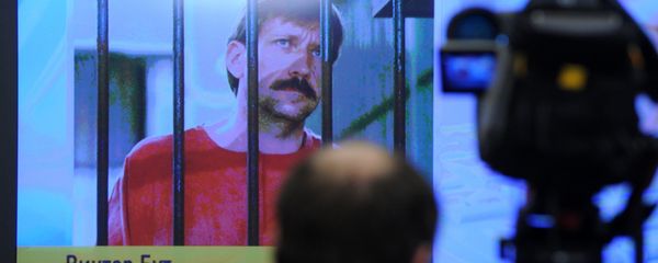 A journalist stands near a screen displaying convicted Russian arms smuggler Viktor Bout in Moscow, on April 12, 2012, during a teleconference with Bout from his US prison - Sputnik International