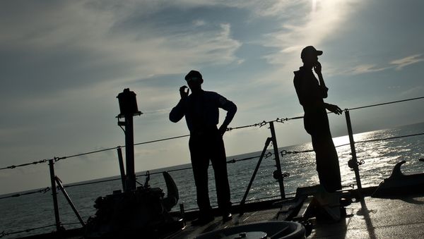 Royal Malaysian Navy personnel are silhoutted as they stand aboard a naval ship during a search and rescue mission for boat-people, near the Thai-Malaysia border north of Langkawi island on May 28, 2015 - Sputnik International