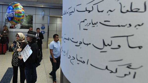 Silvia Sadjadi (L) who migrated from Iran, waits for a family member to arrive beside a arabic sign,after the immigration ban imposed by U.S - Sputnik International