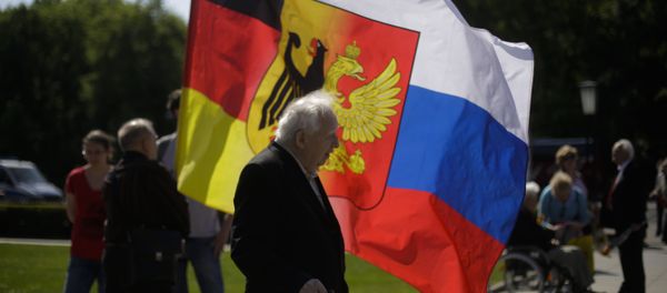 An old man stands in front of a combination of German and Russian national flags prior to a wreath laying ceremony at a Russian War Memorial to commemorate the end of World War II 71 years ago, at the district Tiergarten in Berlin, Germany, Monday, May 9, 2016 - Sputnik International