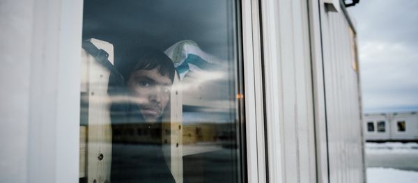 A refugee looks through a window in the sleeping facilities at the arrival centre for refugees near the town on Kirkenes in northern Norway close to the border with Russia on November 11, 2015 A refugee looks through a window in the sleeping facilities at the arrival centre for refugees near the town on Kirkenes in northern Norway close to the border with Russia on November 11, 2015 - Sputnik International