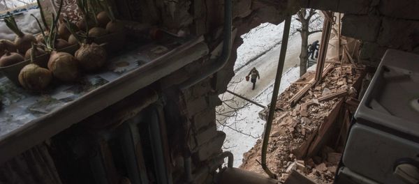 A local resident walking in a street is seen through a hole in an apartment building damaged by shelling in Avdiivka, Ukraine, Saturday, Feb. 4, 2017 - Sputnik International