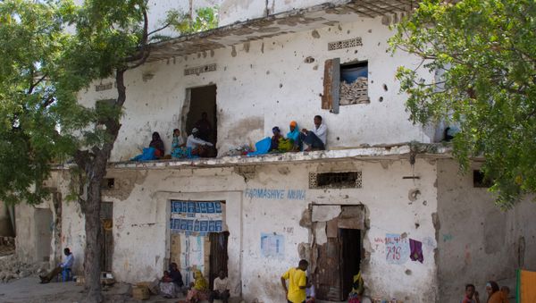 People rest along a bullet-ridden building in Mogadishu, Somalia People rest along a bullet-ridden building in Mogadishu, Somalia - Sputnik International