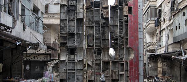 This file photo taken on March 14, 2015 shows a young boy walking past a makeshift barricade made of wreckages of buses to obstruct the view of regime snipers and to keep people safe in the rebel-held side of the northern Syrian city of Aleppo. - Sputnik International