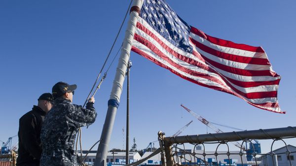 Sailors assigned to the Arleigh Burke-class guided-missile destroyer USS John S. McCain (DDG 56) lower the ensign as the ship gets under way for a routine patrol. McCain is forward deployed to the U.S. 7th Fleet area of responsibility in support of security and stability in the Indo-Asia-Pacific region - Sputnik International
